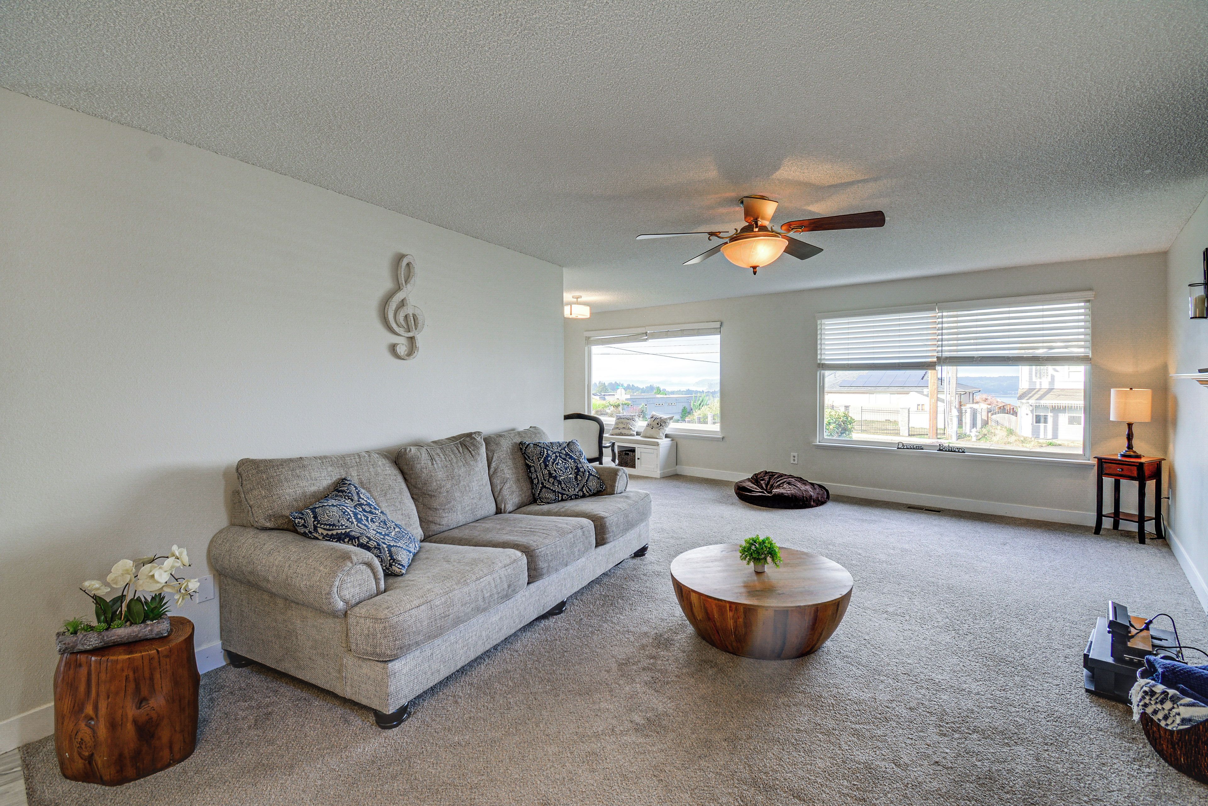 A living room with a grey sofa, a wooden coffee table, and a ceiling fan.