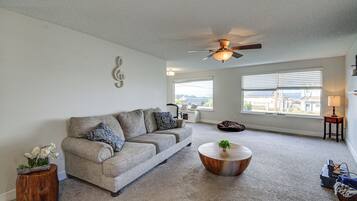 A living room with a grey sofa, a wooden coffee table, and a ceiling fan.