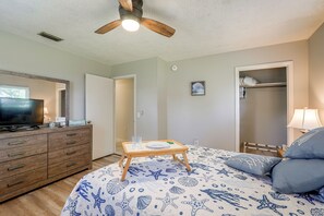 Ein Schlafzimmer mit einem Bett, einem Schminktisch, einem Fernseher und einem Deckenventilator.