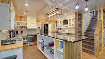 A modern kitchen with a central island, built-in appliances, and a wooden staircase.