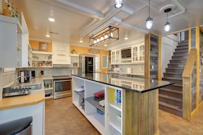 A modern kitchen with a central island, built-in appliances, and a wooden staircase. - Harbour View - Lake Cabin w/ Game Room & Fire Pit (Odessa)