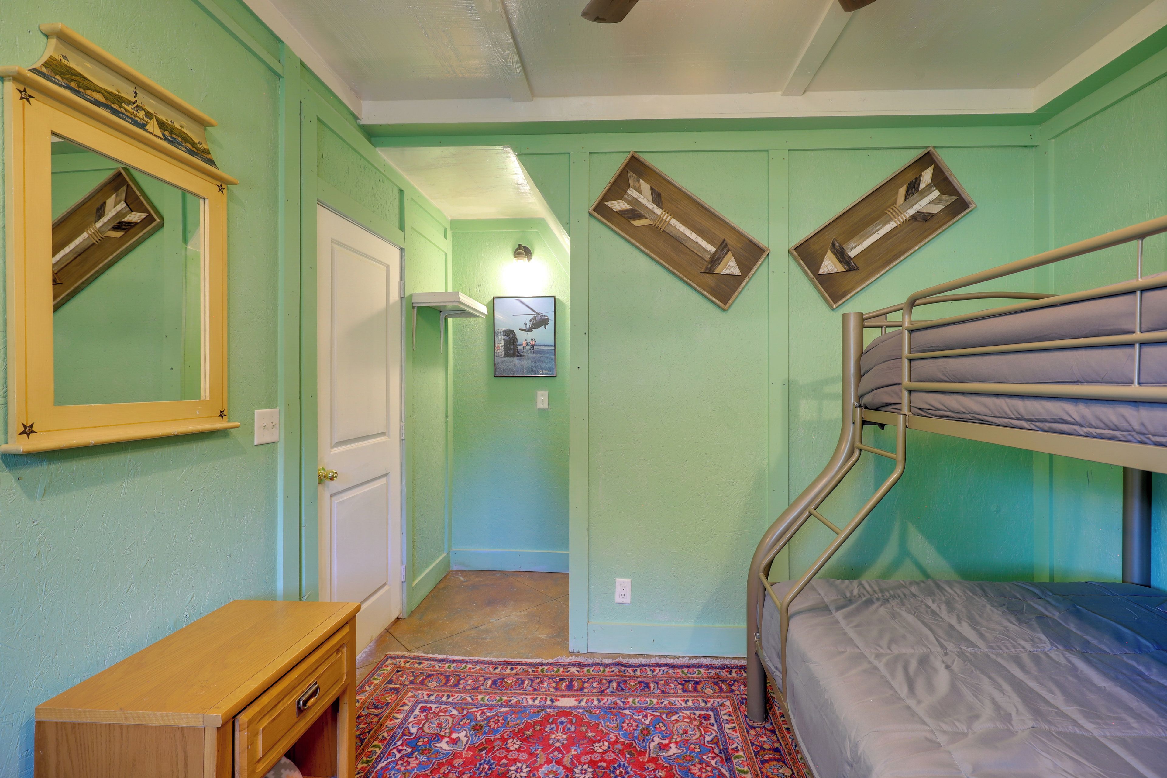 A room with a bunk bed, a wooden dresser, a mirror with a decorative frame, and a patterned rug.