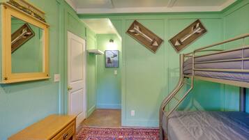 A room with a bunk bed, a wooden dresser, a mirror with a decorative frame, and a patterned rug.