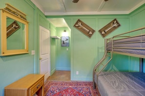 A room with a bunk bed, a wooden dresser, a mirror with a decorative frame, and a patterned rug. - Harbour View - Lake Cabin w/ Game Room & Fire Pit (Odessa)