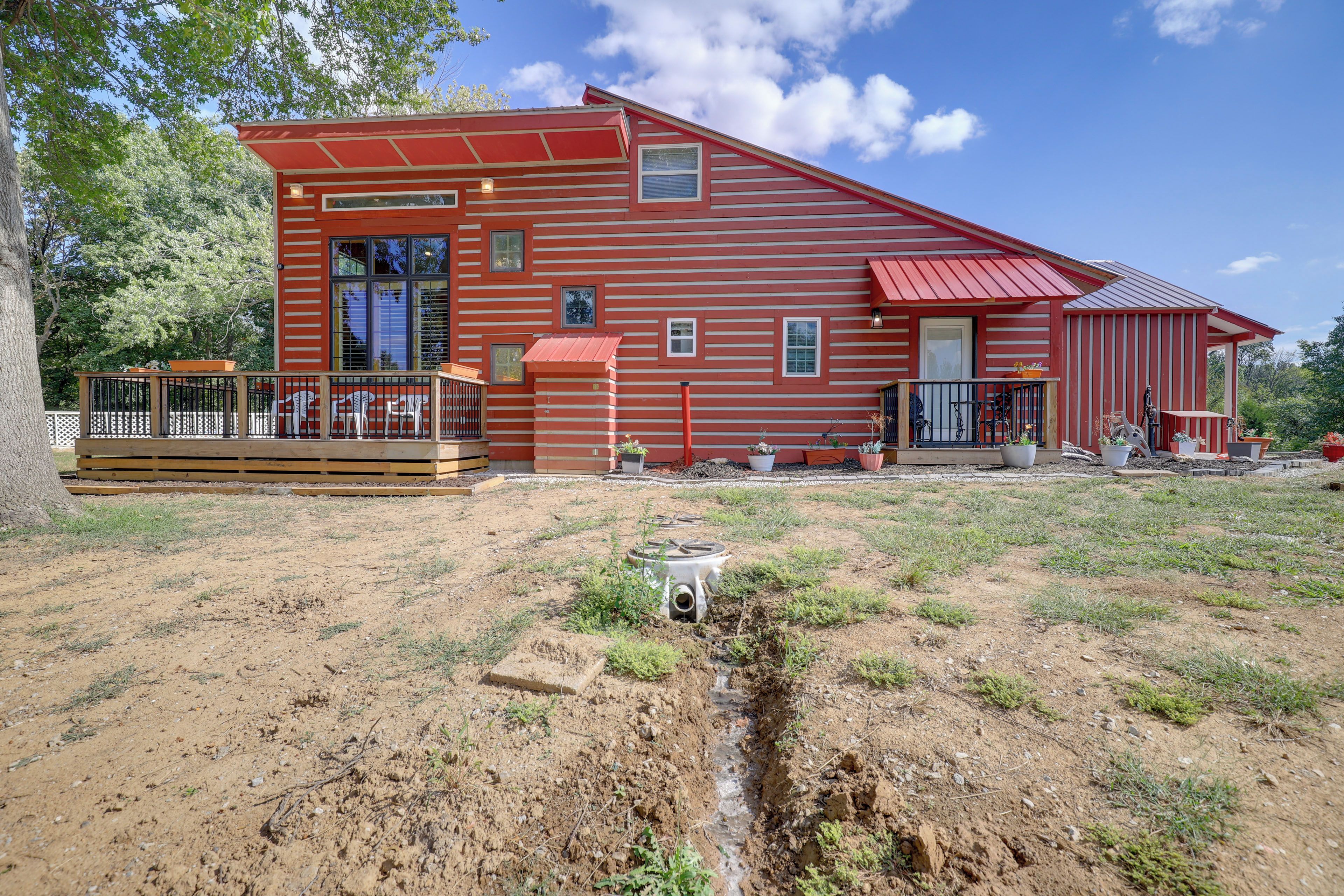 A red wooden house with a deck and a small garden area.
