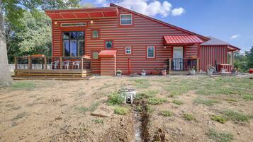 A red wooden house with a deck and a small garden area.