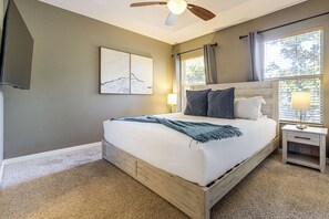 Ein Schlafzimmer mit Bett, Nachttisch, Wandbild und Deckenventilator.