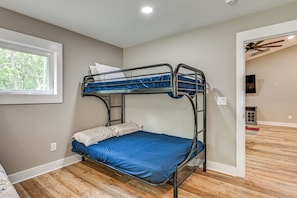 A bunk bed with a blue mattress in a room with wooden flooring and a window.