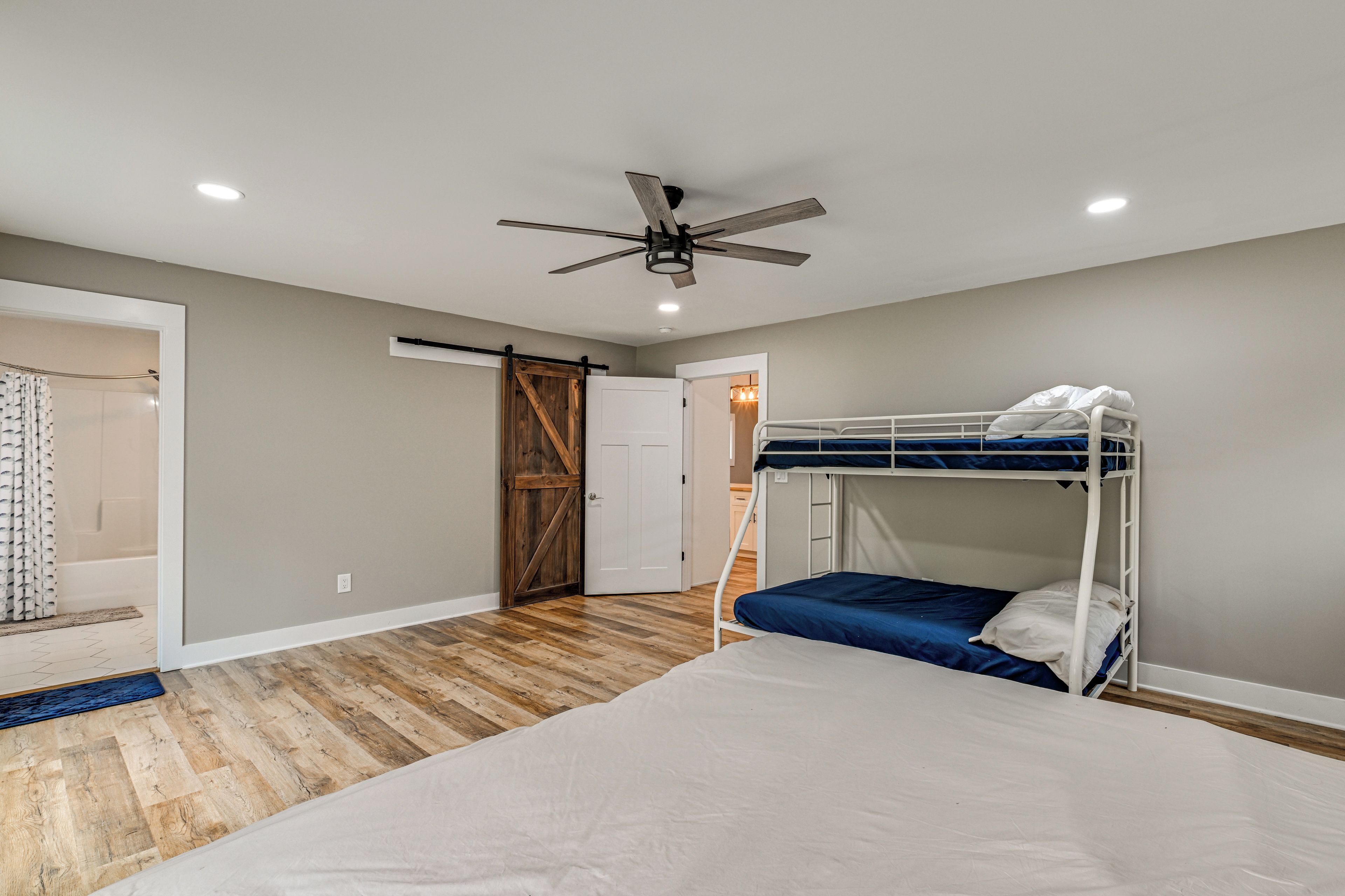 Un dormitorio con una cama litera, un ventilador de techo y una puerta de madera.
