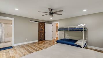 Un dormitorio con una cama litera, un ventilador de techo y una puerta de madera.
