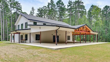 A modern two-story house with a covered patio area and a large deck.