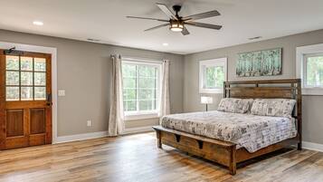 Un dormitorio con cama de madera, ventilador de techo y ventana con cortinas.