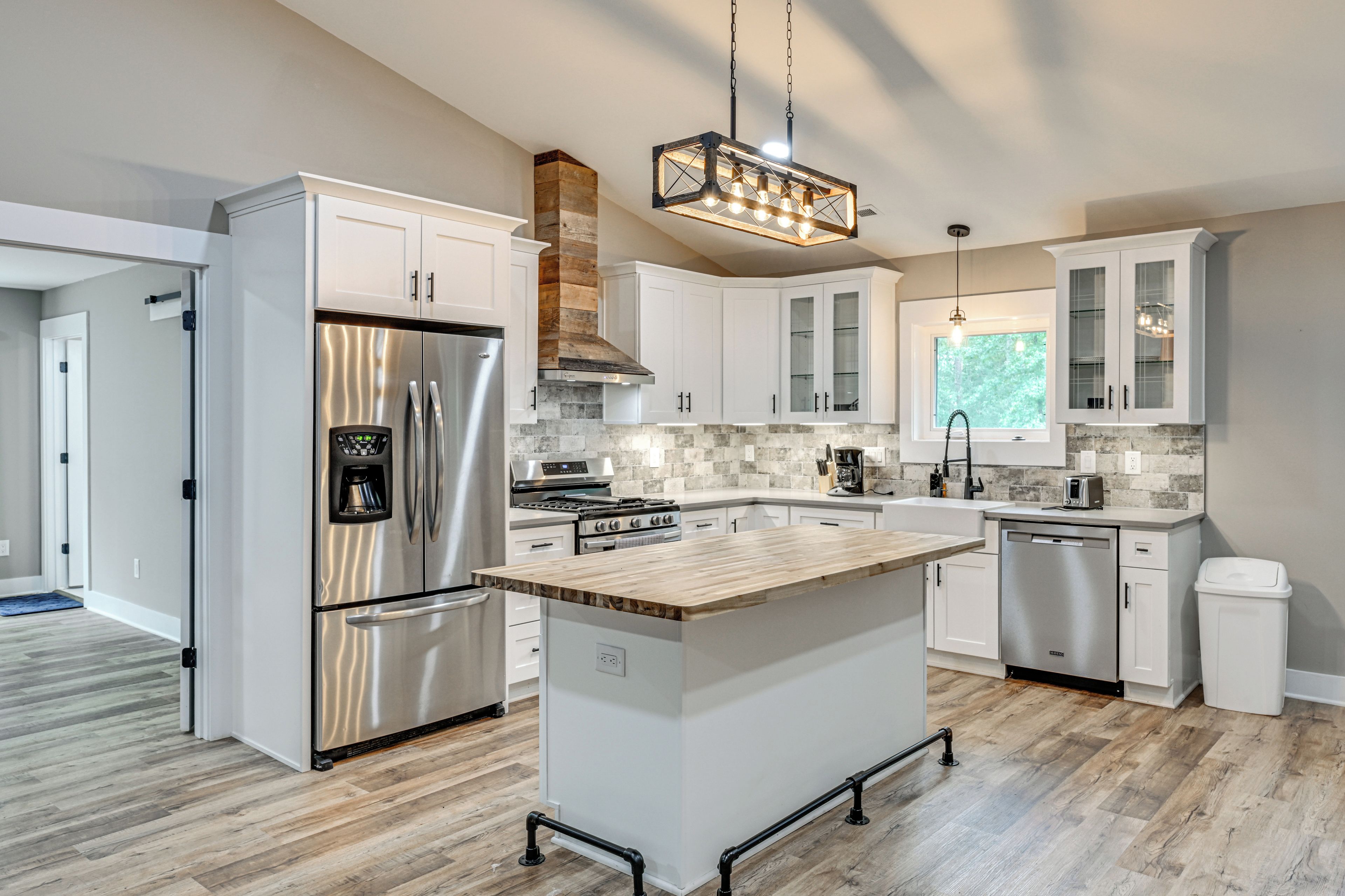 A modern kitchen with stainless steel appliances, a central island, and a view to the outdoors.