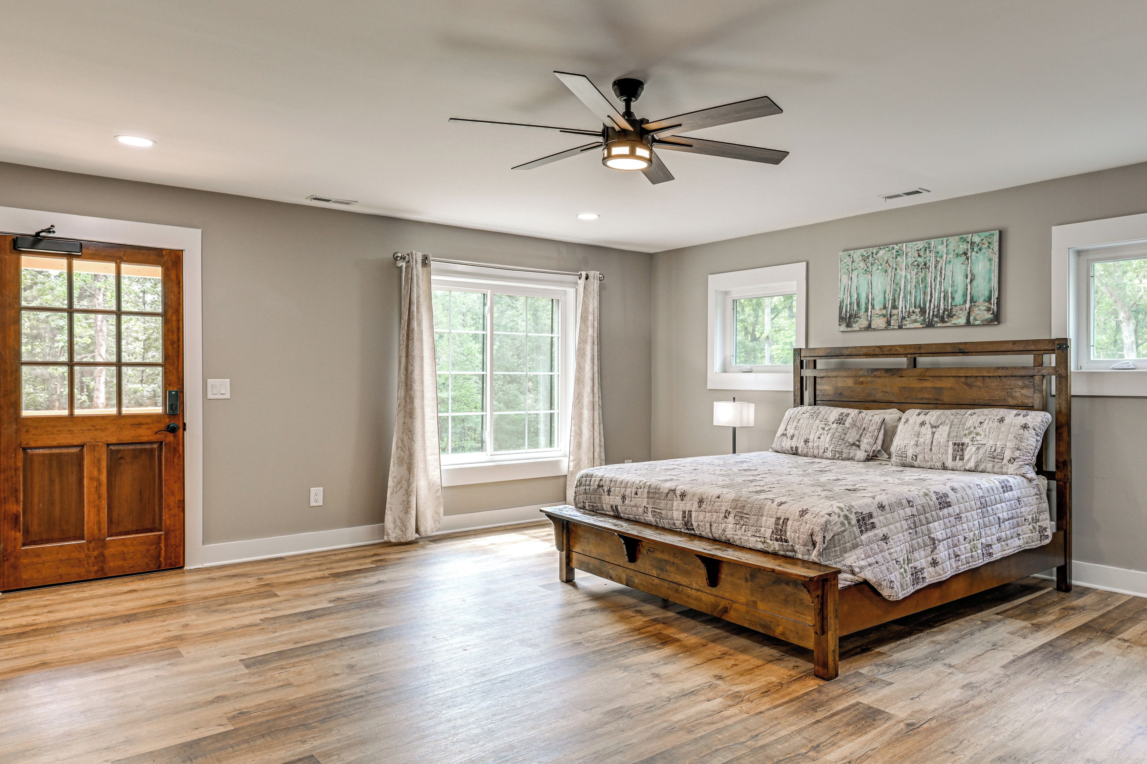 A bedroom with a wooden bed, a ceiling fan, and a large window with curtains.