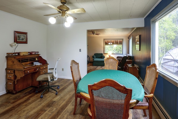 A dining area with a wooden table, chairs, and a ceiling fan.