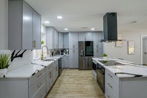A modern kitchen with grey cabinets, stainless steel appliances, and a central island. - Cozy Home Base Btwn Dallas & Fort Worth (Bedford)