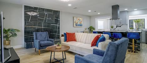 Un salon moderne avec un canapé blanc, des fauteuils bleus et une table basse.
