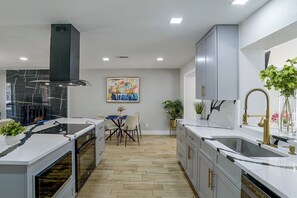 A modern kitchen with a central island, built-in oven, and a dining area with a table and chairs. - Cozy Home Base Btwn Dallas & Fort Worth (Bedford)