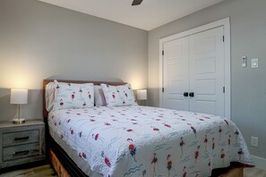 A bedroom with a bed, bedside tables, a door, and a wall-mounted light switch. - Cozy Home Base Btwn Dallas & Fort Worth (Bedford)