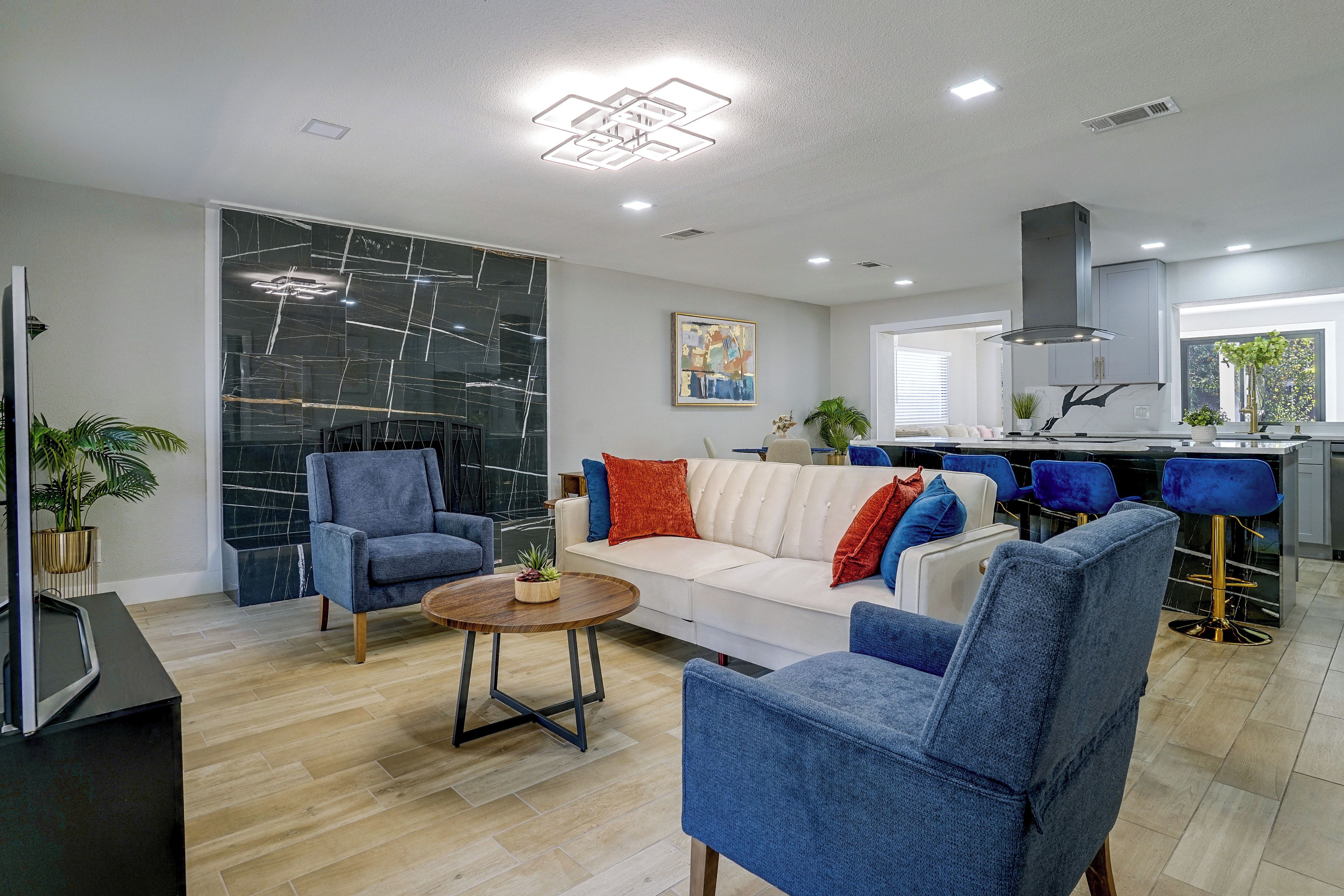 Un salon moderne avec un canapé blanc, des fauteuils bleus et une table basse.