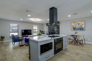 A modern kitchen with a central island, built-in oven, and a black range hood. - Cozy Home Base Btwn Dallas & Fort Worth (Bedford)