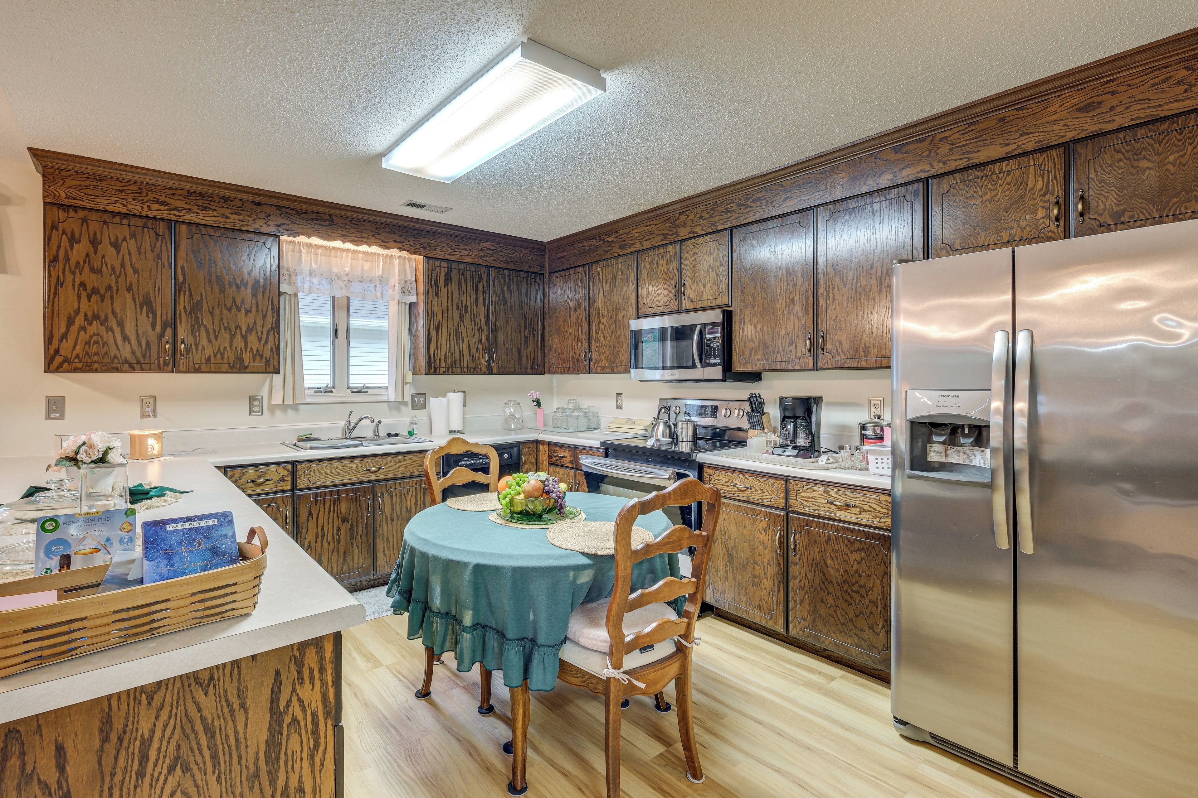 A modern kitchen with wooden cabinetry, stainless steel appliances, and a dining area with a table set for two.