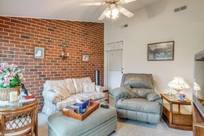 A living room with a brick wall, a sofa, a chair, a coffee table, and a lamp. - Private Yard & Patio! Hopewell Extended Stay (Hopewell)