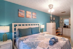 A bedroom with a bed, nightstands, a desk, and a kitchenette. - Bayfront Unit w/ Hot Tub & Dock Access! (Fort Walton Beach)