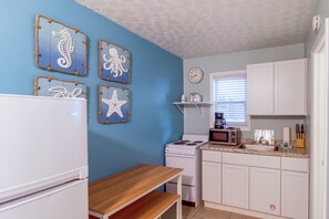 A kitchen with white cabinets, a stove, a microwave, and a sink. There are decorative wall hangings and a clock on the wall. - Bayfront Unit w/ Hot Tub & Dock Access! (Fort Walton Beach)