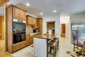 A modern kitchen with wooden cabinets, stainless steel appliances, and a central island with bar stools. - Brevard Retreat w/ Hot Tub & Copper Soaking Tub (Brevard)