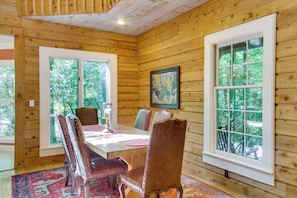 A wooden-paneled room with a dining table and chairs, large windows, and a framed picture on the wall. - Brevard Retreat w/ Hot Tub & Copper Soaking Tub (Brevard)
