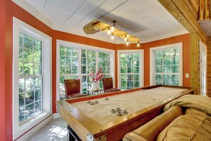 A pool table in a room with large windows, wooden ceiling beams, and a view of trees. - Brevard Retreat w/ Hot Tub & Copper Soaking Tub (Brevard)
