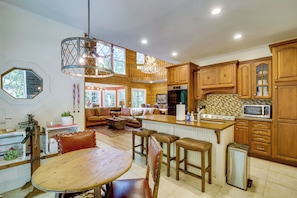 A spacious kitchen with wooden cabinets, a dining area with a wooden table and chairs, and a living room with a sofa and a chandelier. - Brevard Retreat w/ Hot Tub & Copper Soaking Tub (Brevard)