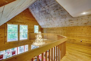 Ein Holzinnenraum mit Balkon, großen Fenstern und einer hängenden Leuchte.
