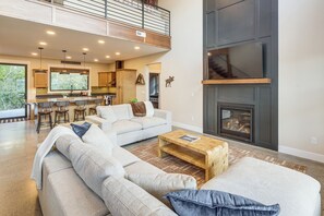 A spacious living room with a large sofa set, a fireplace, and a kitchen area with a bar. - Mtn Views & On-site Creek! Red Lodge Gem (Red Lodge)