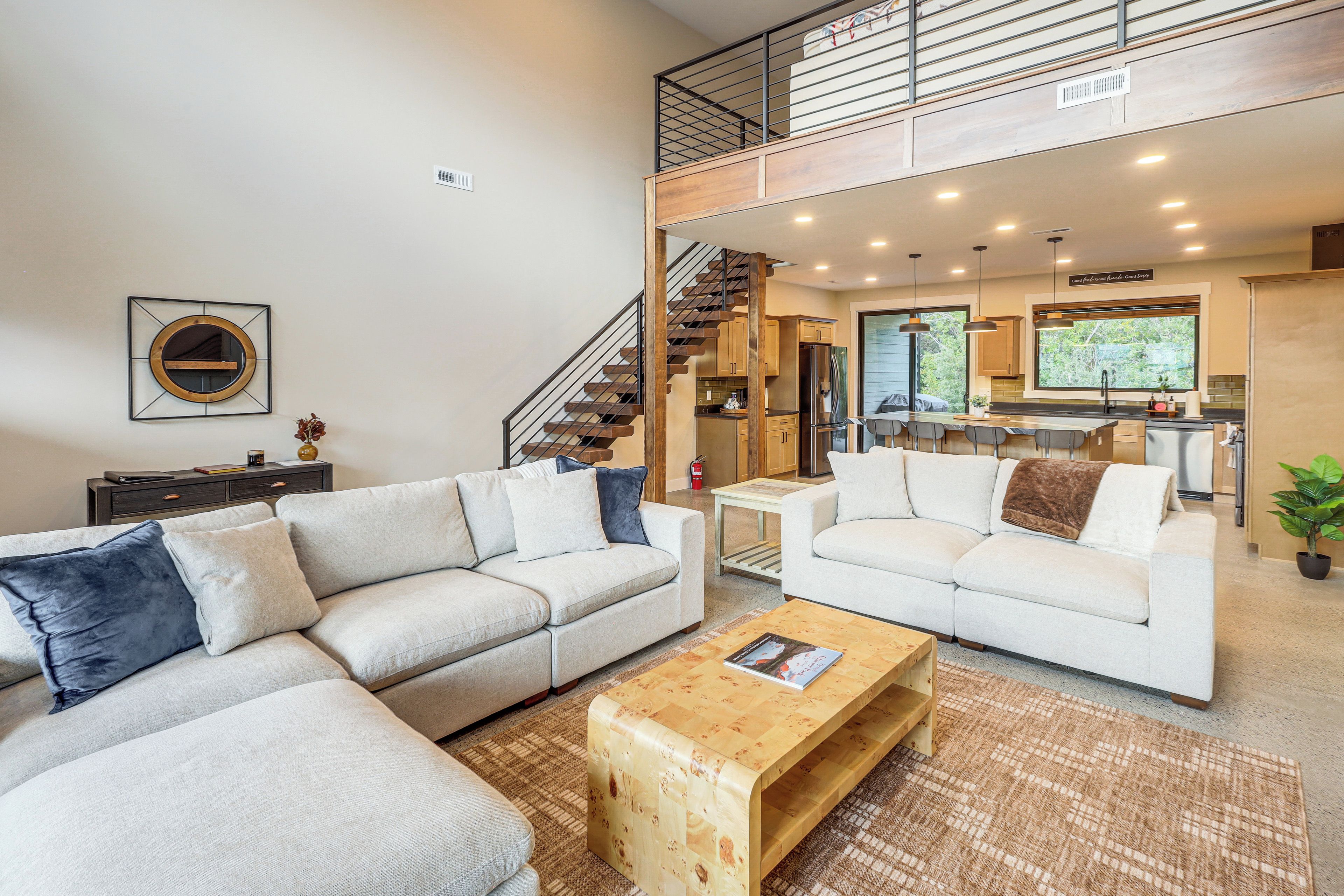 A spacious living area with two sofas, a coffee table, and a staircase leading to an upper level.