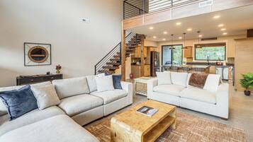 A spacious living area with two sofas, a coffee table, and a staircase leading to an upper level.