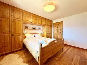 Ein Schlafzimmer mit einem hölzernen Bett, eingebauten Holzschränken und einer runden Deckenleuchte.