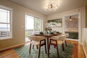 Un coin repas avec une table en bois, quatre chaises, un lustre et un tableau au mur.