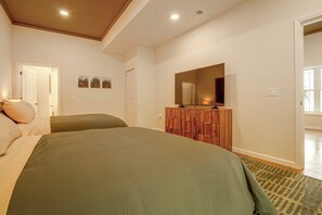 Ein Schlafzimmer mit zwei Betten, einem Schminktisch, einem Spiegel und einer Tür zu einem anderen Raum.