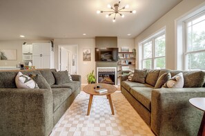 A living room with two sofas, a coffee table, a fireplace, and a bookshelf. - River Views & Gas Fire Table: Maiden Rock Retreat (Maiden Rock)