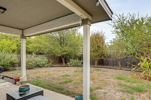 A covered patio area with a table and chairs, surrounded by a wooden fence and various plants. - Easy Airport Access! Austin Home w/ Patio (Austin)