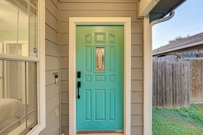 A turquoise door with a glass panel, a keypad lock, and a 'NO SOLICITING' sign.
