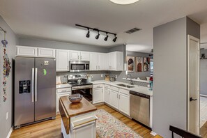 A modern kitchen with white cabinets, stainless steel appliances, and a wooden island. - Easy Airport Access! Austin Home w/ Patio (Austin)
