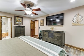 Ein Schlafzimmer mit Bett, Deckenventilator, Fernseher und Kommode.
