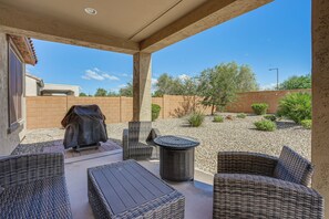 Eine Terrasse im Freien mit Korbmöbeln, einem Grill und Blick auf die umliegende Landschaft.
