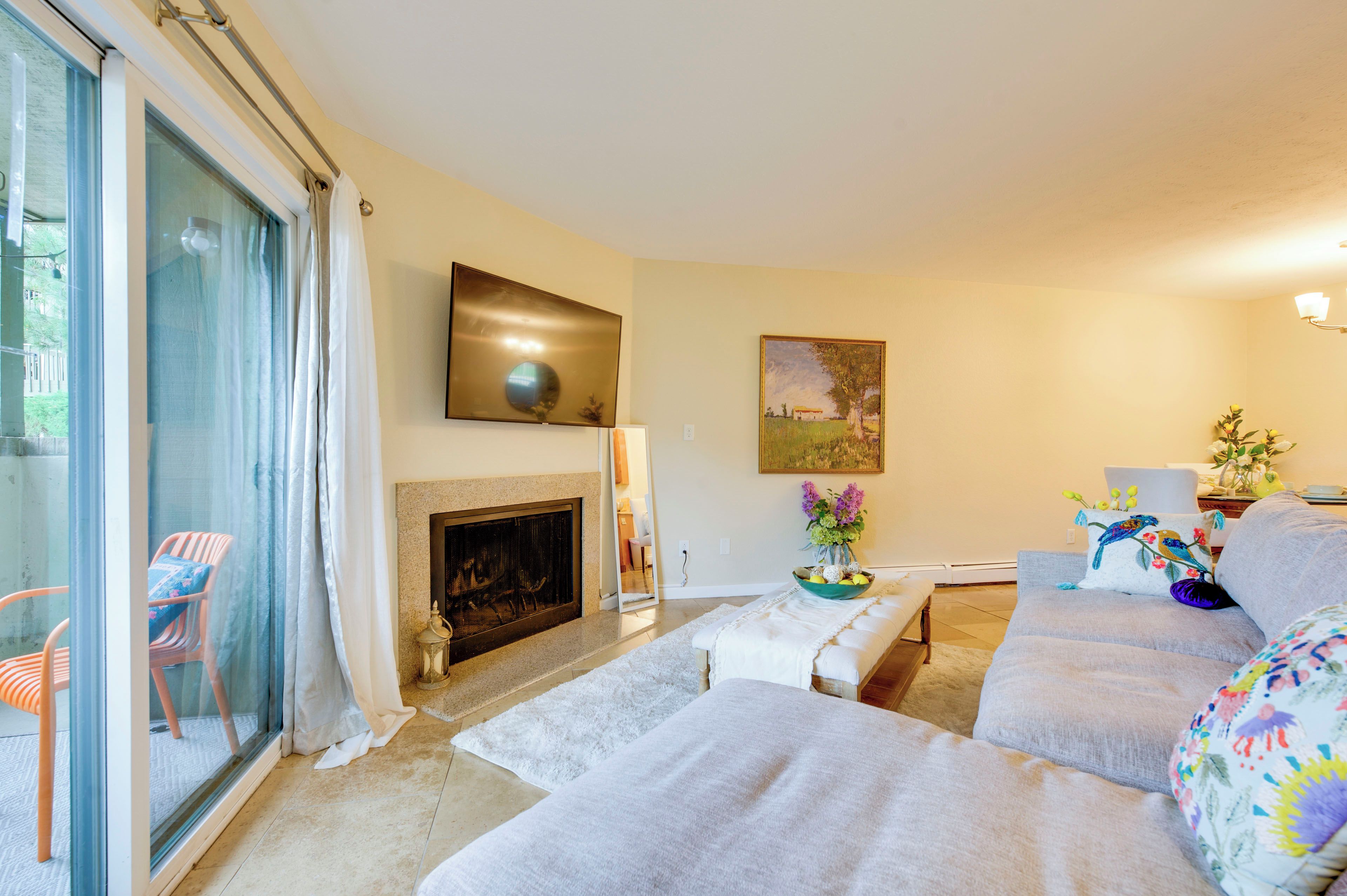 A living room with a fireplace, a sofa, a chair, and a large window.