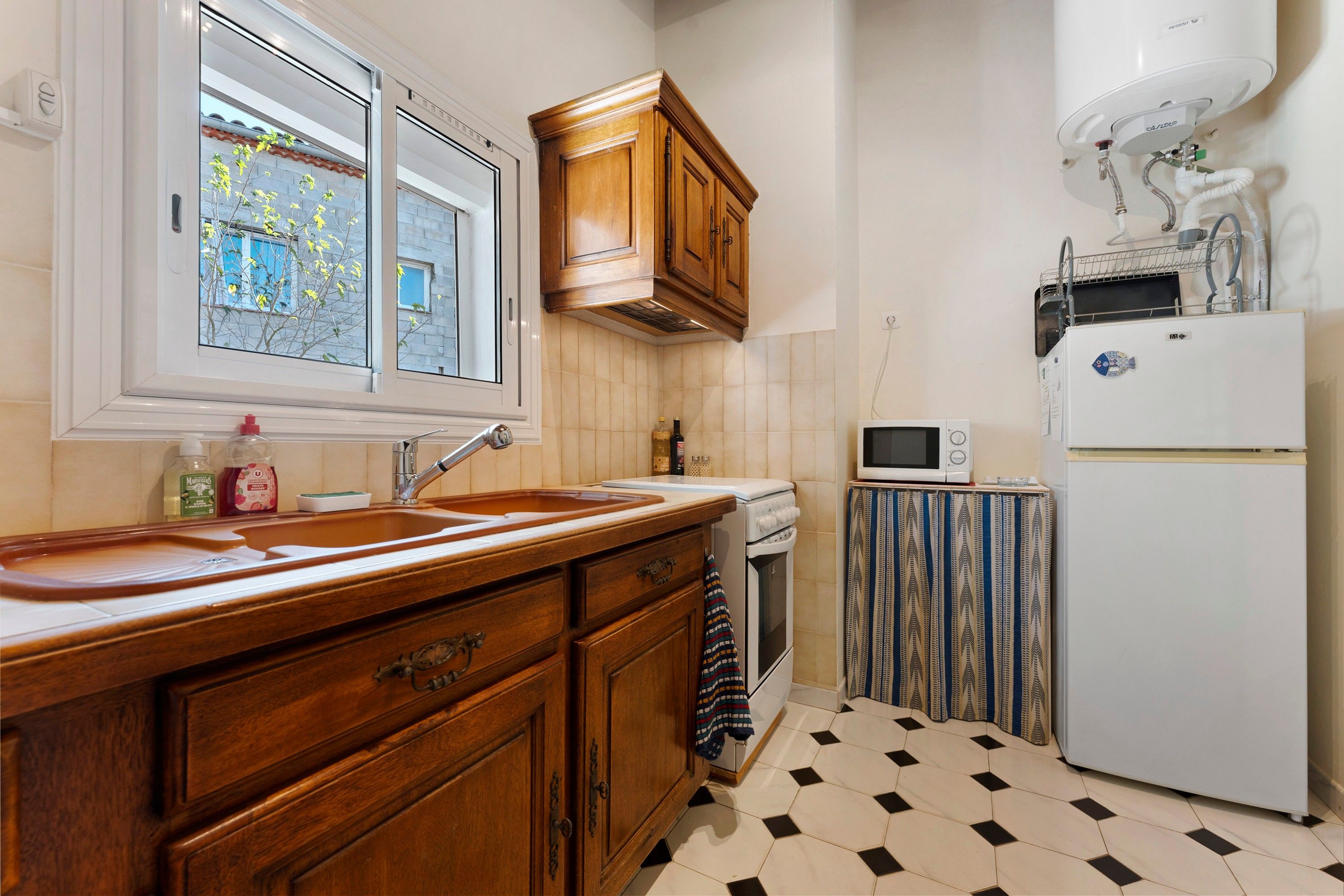 Une cuisine avec des meubles de rangement en bois, un four encastré, un four à micro-ondes et un réfrigérateur.