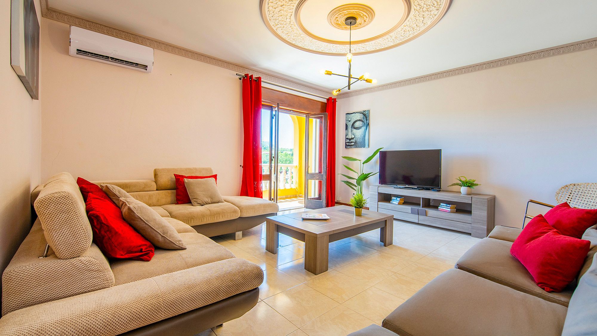 A living room with a sofa, a coffee table, a TV, and a plant.