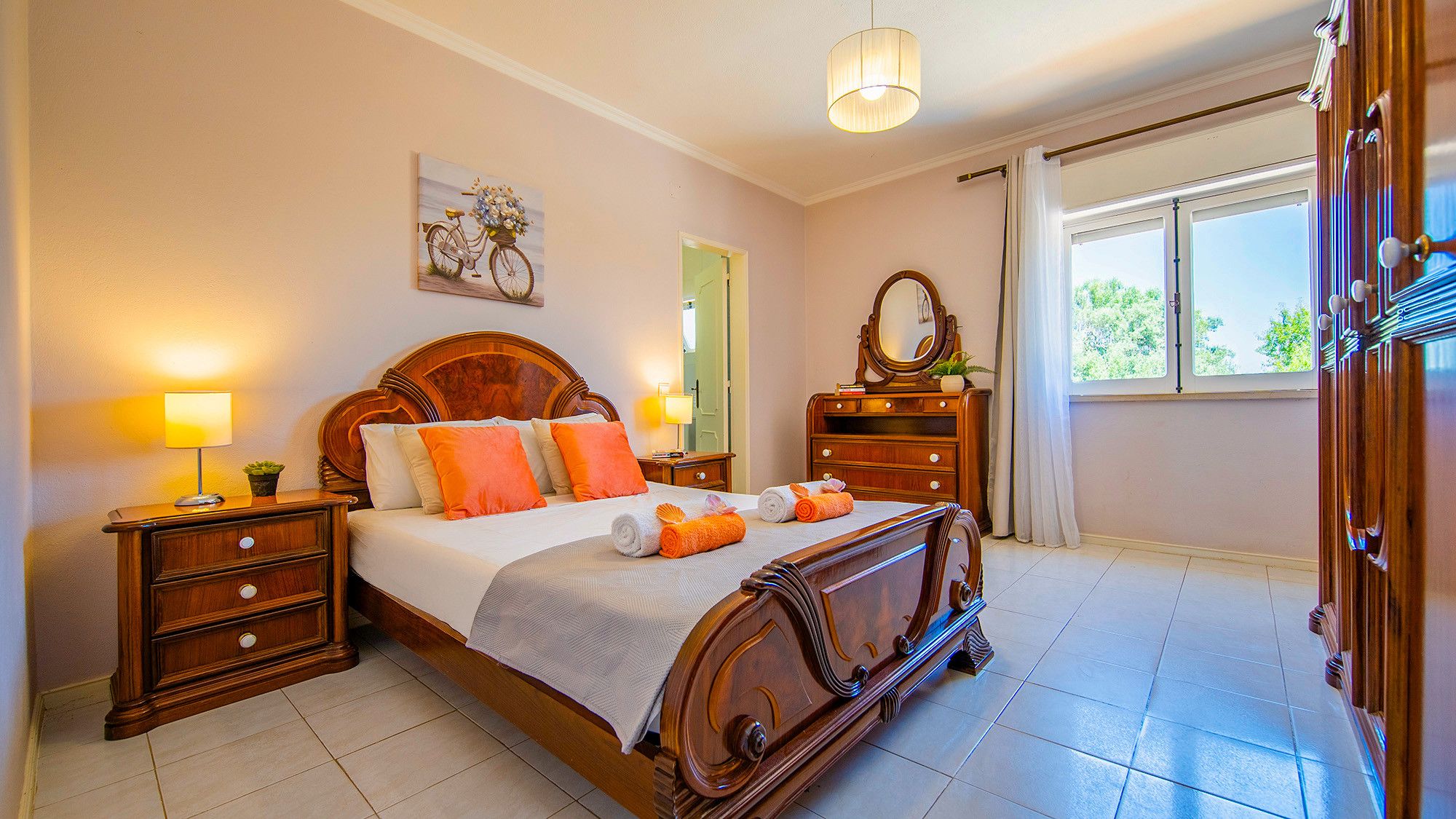 Een slaapkamer met een houten bed, nachtkastjes, een spiegel en een raam met gordijnen.